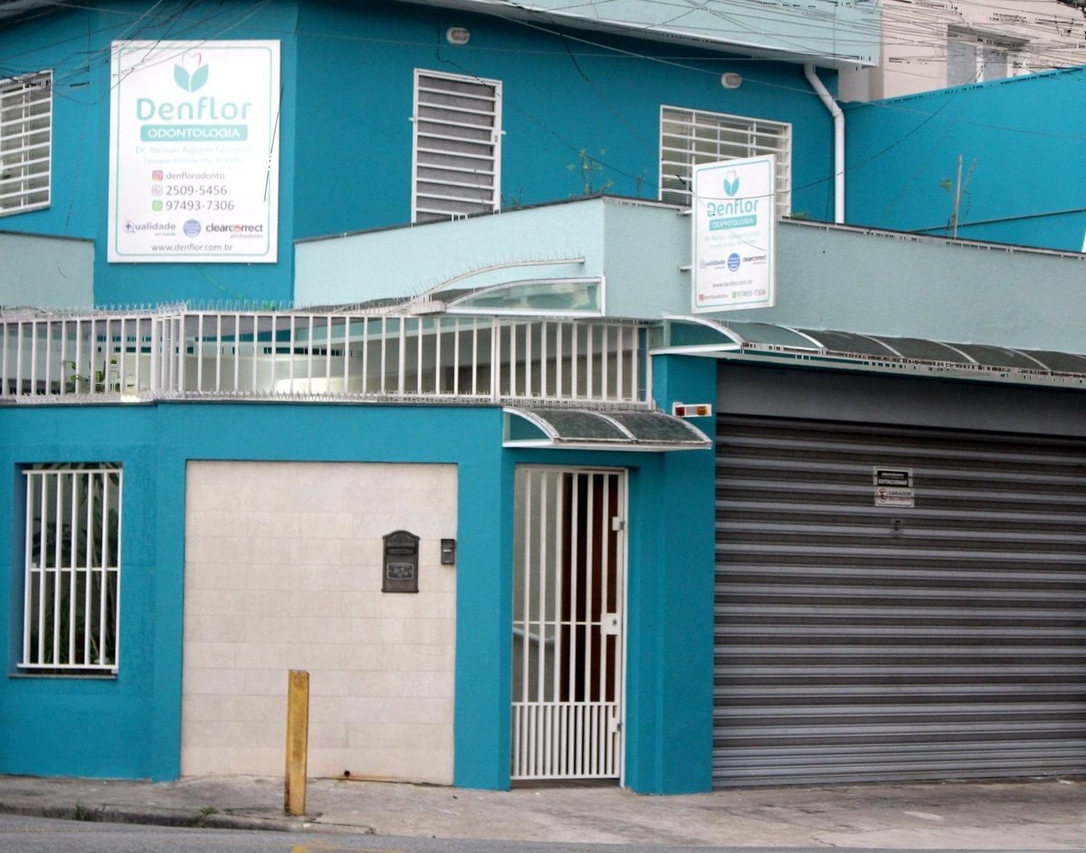 Fachada turquesa da Denflor Odontologia, com a placa da clínica, no Nova Petrópolis